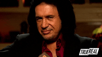 Reality TV gif. Gene Simmons on Gene Simmons: Family Jewels smiles at us and raises an eyebrow like he's not even trying to hide he's flirting.