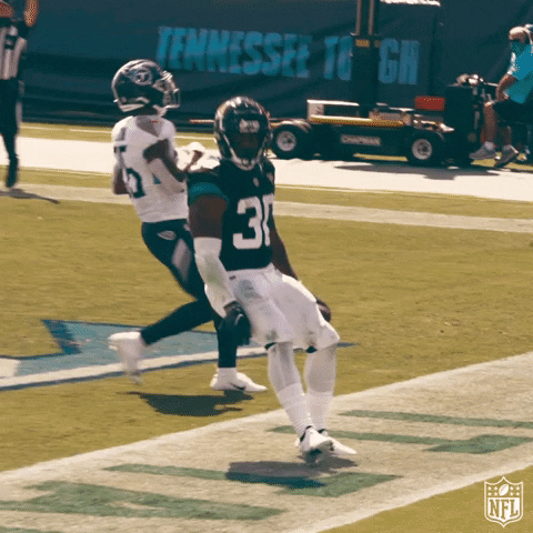 Sports gif. James Robinson from the Jacksonville Jaguars holds a football and comes to an abrupt stop on the field as he points out into the crowd.