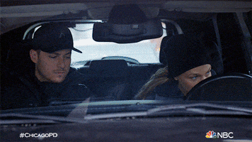 TV gif. Jesse Lee Soffer as Jay and Tracy Spiridakos as Detective Hailey in Chicago PD. They're on a stakeout in a car and Hailey is looking out her window and Jay takes this chance to pick up her coffee and take a sip. She catches him and stares.