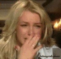Celebrity gif. Britney Spears cries, leaning back and covering her face with her hands.