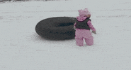Video gif. A little girl is standing in front of a sledding tube when all of a sudden, a golden retriever army crawls by with their legs fully extended in a sploot.  Both the little girl and her father and shocked at the sight.