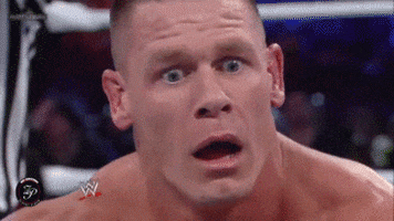 Sports gif. John Cena in a WWE match looks down with wide eyes and a face full of confusion. He furrows his brows as he tries to process what just happened.
