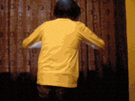 Video gif. Man facing away from us sweeps open the curtains on a window, then falls backward as light streams in.