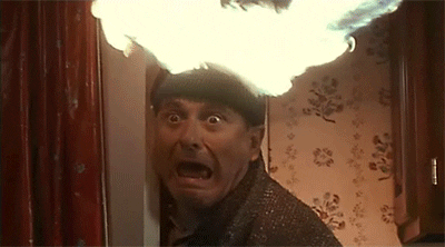 Movie gif. Joe Pesci as Harry in Home Alone. He's hiding behind a wall and his head is on fire. His face gapes with shock as he blinks.