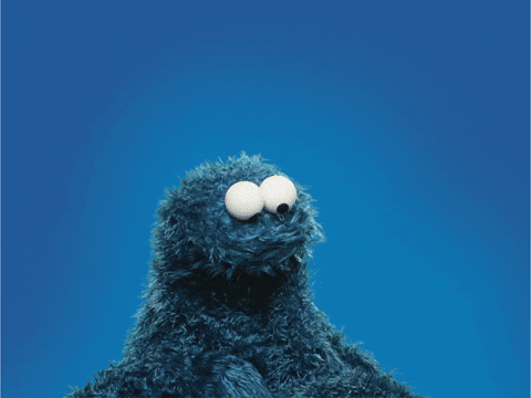 Cookie Monster from Sesame Street holds out a red paper heart.