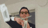 TV gif. A cheerful man in a suit with sunglasses makes quick scraping motions over a stack of money, throwing bills into the air.