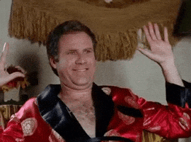 Movie gif. Actor Will Ferrell as Chaz in the Wedding Crashers sits in a red robe. He excitedly punches the air with both hands, and gives a cheeky smile that widens as he celebrates. 