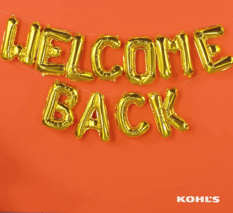 Ad gif. A sign made out of foil balloons hangs on the wall and a woman on a desk chair rolls into frame, smiling and giving a thumbs up before rolling off screen. Text, "Welcome Back"