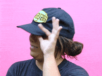 Video gif. A woman wearing a black baseball cap tilts the visor up slightly, half smiles with embarrassment or disgust, and rocks back slightly, rolling her eyes to the left in a look of disbelief. 