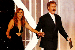 Celebrity gif. Kristen Wiig and Will Ferrell walk out hand in hand to present at the Golden Globes and stare at their surroundings in exaggerated awe.
