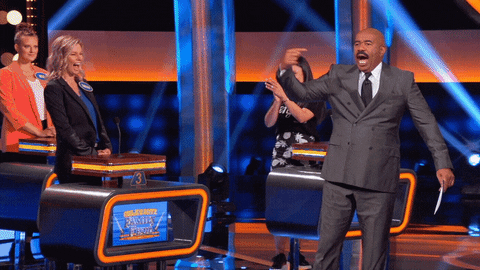 Reality TV gif. Steve Harvey on Celebrity Family Feud stalks across the stage and points at himself while declaring, "I'm hot!"