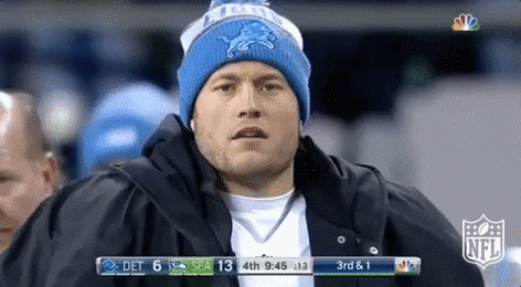 Sports gif. Matthew Stafford of the Detroit Lions wears a winter coat and beanie. He looks at us confused with tight eyebrows and a slightly open mouth.
