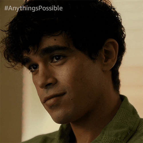 TV gif. Abubakr Ali as Khalid in Anything's Possible. He's staring at someone warmly while a small smile grows on his lips.
