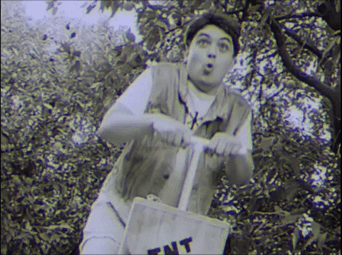 Movie gif. Paul Prado as Turbeaux in Dude Bro Party Massacre III shamelessly presses down on a vintage TNT plunger box yet has a look of exaggerated innocence and covers his mouth as if he is sheepish.