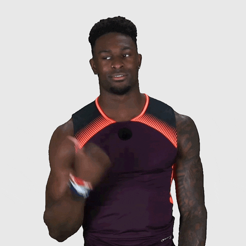 Sports gif. DK Metcalf points with his thumb to the left and gives a side-eye