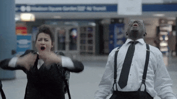TV gif. Actor Hannibal Buress as Lincoln in Broad City falls to his knees in anguished frustration next to Ilana Glazer as Ilana as he screams at the sky. 