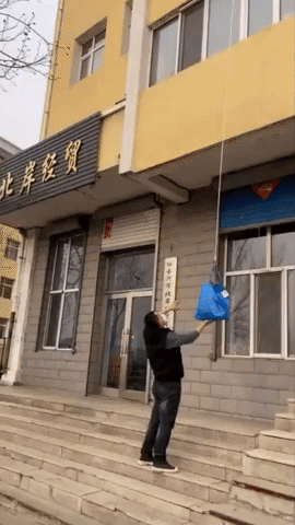 Resident in Northeastern China Hoists Food Through Window as Social Distancing Precaution