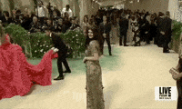 Met Gala 2024 gif. Alexandra Daddario poses for the cameras, one way, then the other, wearing an edgy golden Dior Haute Couture gown.