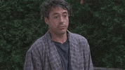 Movie gif. Robert Downey Jr. as Principal Gardner in Charlie Barlett shrugs indifferently in his pajama robes.