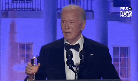 Video gif. President Joe Biden stands behind a podium at the 2024 White House Correspondents' Dinner and raises a champagne glass in a toast. He says "To a free press. To an informed citizenry. To an America where freedom and democracy endure."