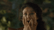 TV gif. Indira Varma as Ellaria on Game of Thrones shrieks, wide-eyed, with horror, her hands crawling down the sides of her face and trembling.