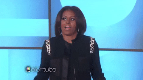 TV gif. Michelle Obama on The Ellen Show. She holds her hands outwards and shrugs her shoulders, looking like she doesn't have a clue what they're referring to.