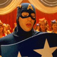 Movie gif. Chris Evans as Captain America. He's vintage Captain America and he announces something before looking at the crowd and walking away to reveal the pinup dancers behind him.