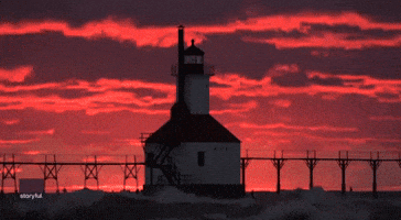 Vibrant Sunset Sets Sky Ablaze as Waves Crash Into Michigan Lighthouse