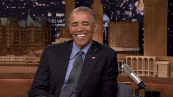 Political gif. On the Jimmy Fallon Show, Barack Obama reacts to something funny, hunching over and laughing.