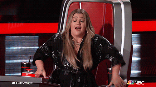 Reality TV gif. Kelly Clarkson on the Voice leaning back in her chair spreading her arms in front of her and blinking hard, blown away.