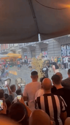 Newcastle Fan Slides Across Rainy MIlan Street 