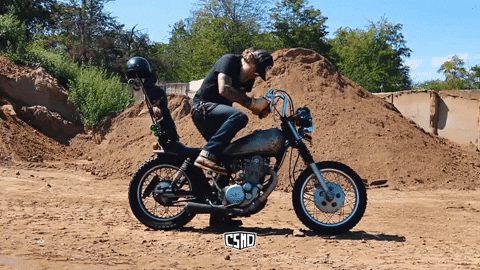 A man kickstarting a motorcycle.