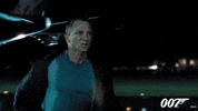 Movie gif. Daniel Craig as James Bond in Casino Royale is drenched in sweat as he runs at full speed down an airplane runway at night. An airplane lands behind him.