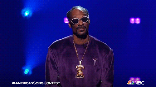 TV gif. Snoop Dogg as a host on American Song Contest looks at us and shrugs with both hands like he's out of answers.
