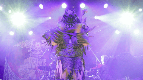 Celebrity gif. Member of Gwar slow claps sarcastically on stage, surrounded by two shining lights.
