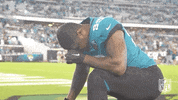 Sports gif. Tyler Lacy of the Jacksonville Jaguars taking a knee, head bowed as if in prayer.