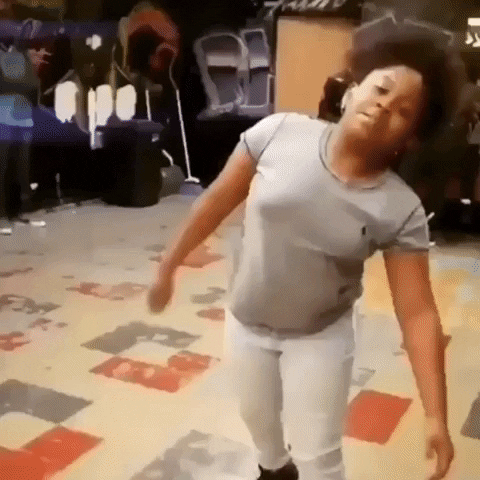 Video gif. A teenage girl begins slowly dancing, then starts going off. Several people in the background watch as she slays, and 2 people cheer her on as they film her from the side.
