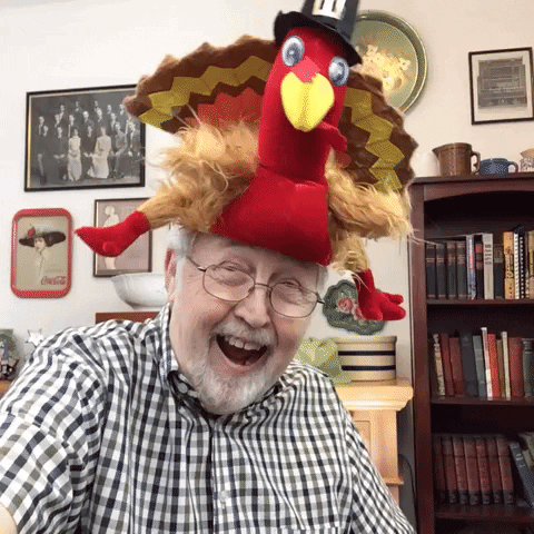 Video gif. Older man wears a fun Thanksgiving turkey hat and playfully gobbles to himself, making himself crack up while the hat comically falls off.