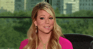 Celebrity gif. Mariah Carey smiles awkwardly while her eyes search around in confusion.