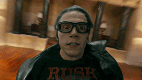 Movie gif. Evan Peters as Quicksilver in X-Men Apocalypse spins towards us so quickly that the background blurs behind him.