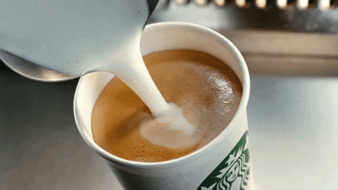 Video gif. Steamed milk pours into espresso on the top of a Starbucks coffee cup. 