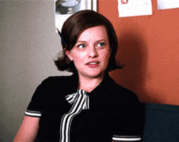 TV gif. Elisabeth Moss as Peggy Olson from Mad Men looks studious with a classy black shirt with stripes running down the middle and a pencil tucked behind her ear. She appears mildly disgusted, as her eyes widen and her lips spread slowly across her face.