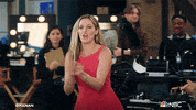 TV gif. Taylor Louderman as Tami on Kenan steps forward among crew workers on a set clapping her hands and cheering loudly.