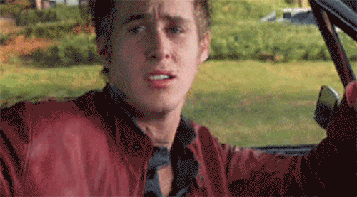 Movie gif. Driving down the street, Ryan Gosling as Richard in Murder by Numbers raises an eyebrow at us as he dances flirtatiously, then breaks into a smile.
