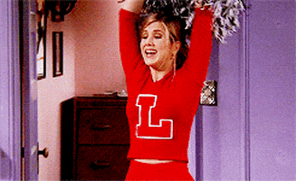 Friends gif. Jennifer Aniston as Rachel dressed as a cheerleader raises her arms and cheers, holding pompoms.
