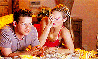 Movie gif. Lying in a bed next to Justin Walker as Christian in Clueless, Alicia Silverstone as Cher starts running her fingers through her hair and then falls off the bed