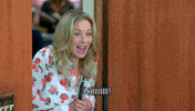 TV gif. Christina Applegate as Gail Budnick on The Grinder steps into a room as she nervously says, “Hiiiiii!”