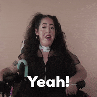 Reaction gif. A Disabled white woman with muscular dystrophy with wavy brown half up half down with two pigtails on top, seated in her motorized wheelchair, nods her head with attitude saying, "Yeah!"