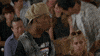 Movie gif. A scene from Half Baked. In an auditorium full of seated people, a standing man in a backward beige cap points at us as he speaks. Text, "Boo this man!" The man pulls off his hat and throws it, stirring the crowd to throw more things. Scrolling text, "Boo."