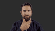 Video gif. Jimmy Lavalle from The Album Leaf strokes his beard stares at us as he thinks.